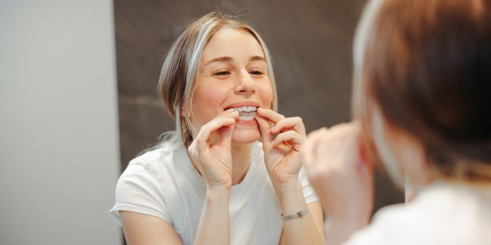 Woman Taking off Her Clear Retainer in the Bathroom Mirror